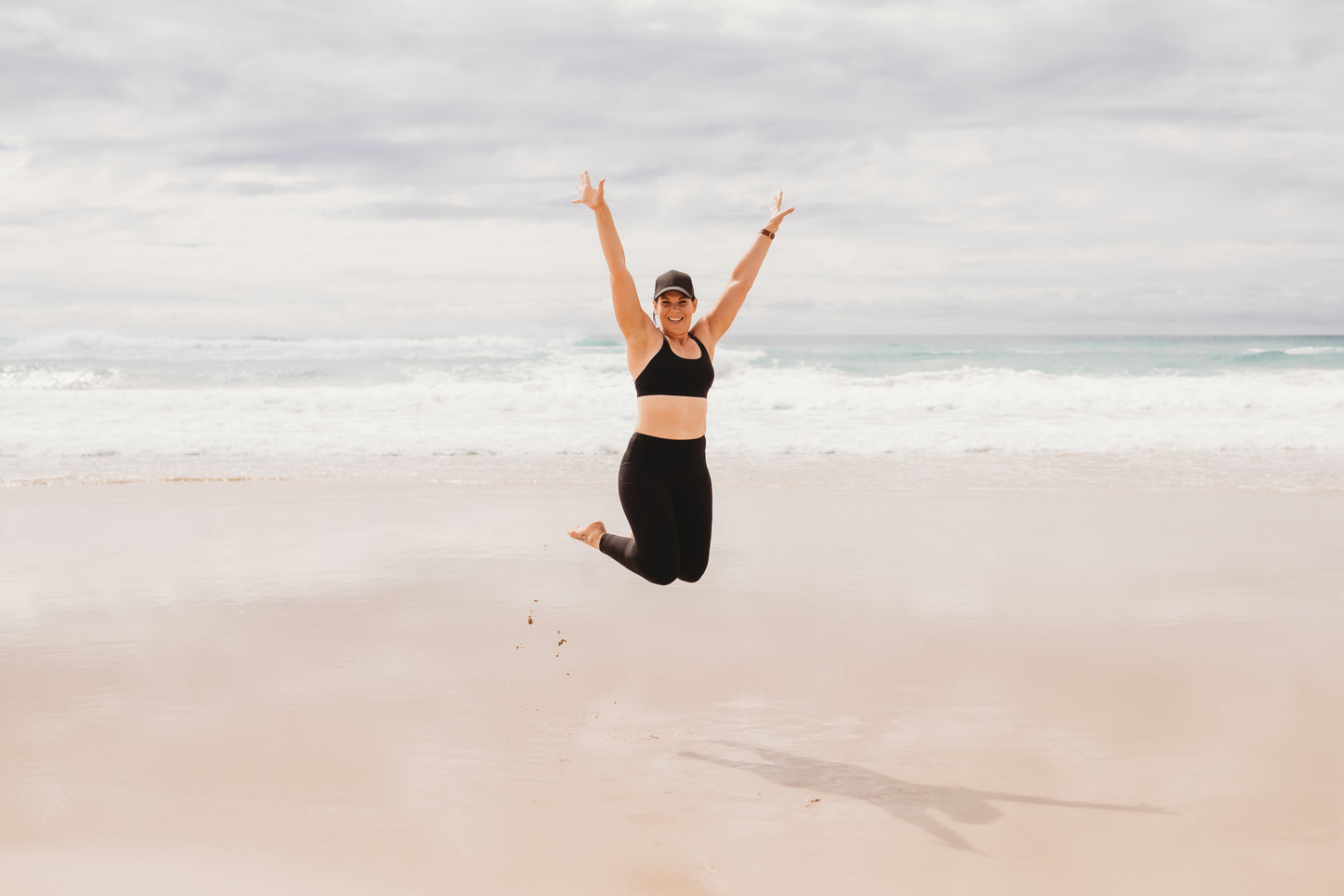 Women at the beach wearing the marlz and me Classic Black Cross Sports Bra and Classic Black Full Length Tights at the beach on a beautiful sunny day.