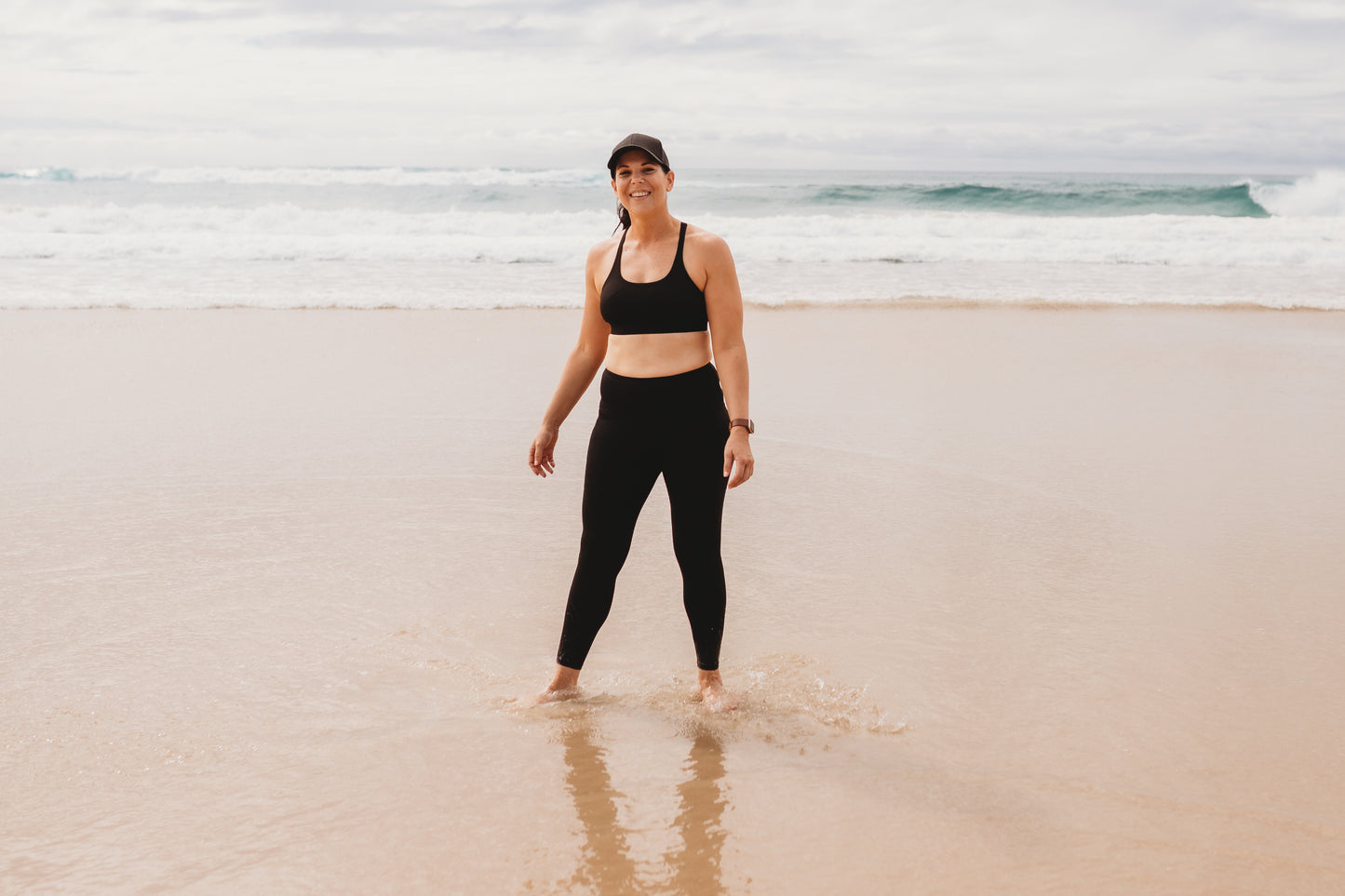 Women at the beach wearing the marlz and me Classic Black Cross Sports Bra and Classic Black Full Length Tights at the beach on a beautiful sunny day.
