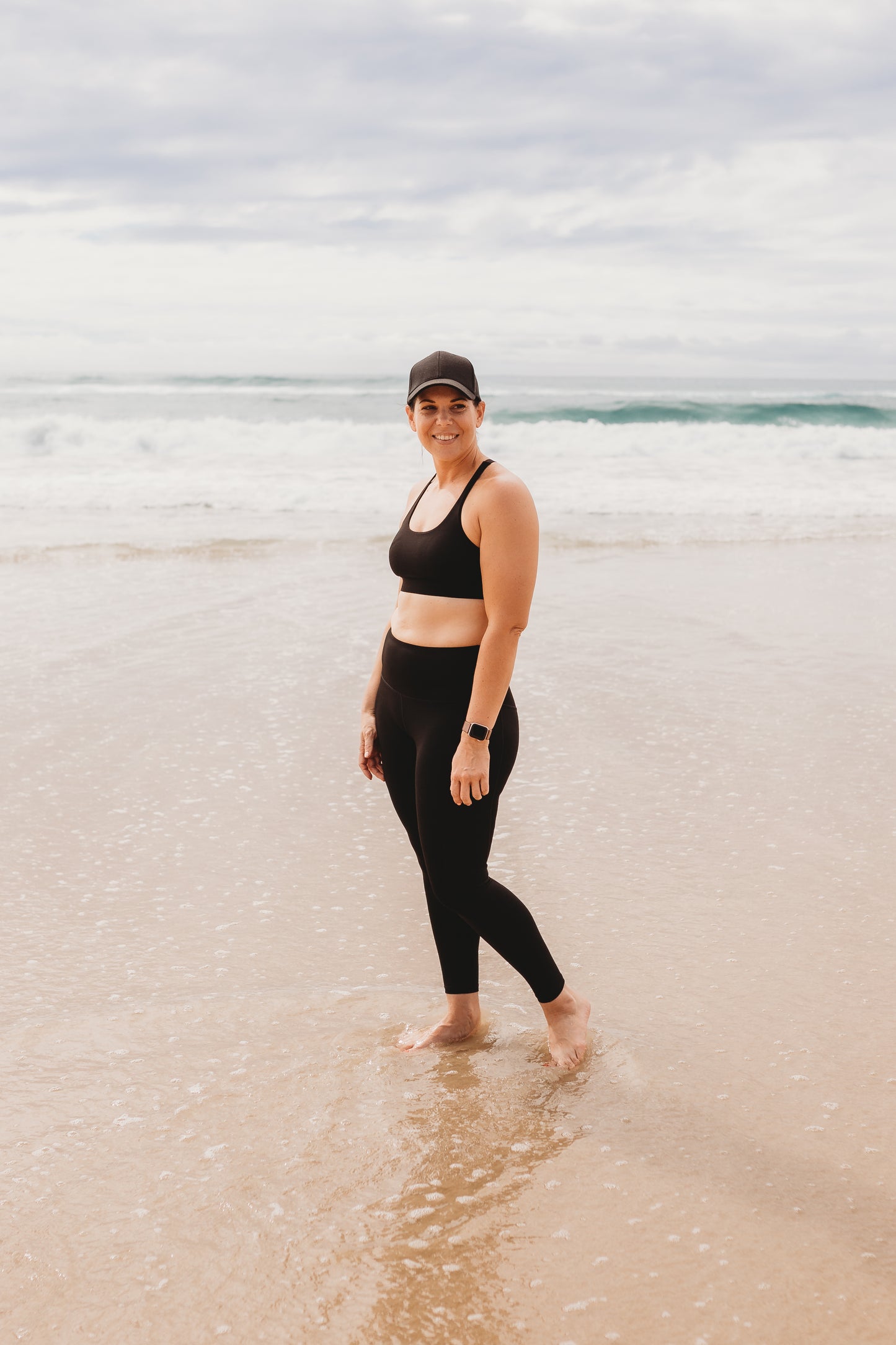Women at the beach wearing the marlz and me Classic Black Cross Sports Bra and Classic Black Full Length Tights at the beach on a beautiful sunny day.