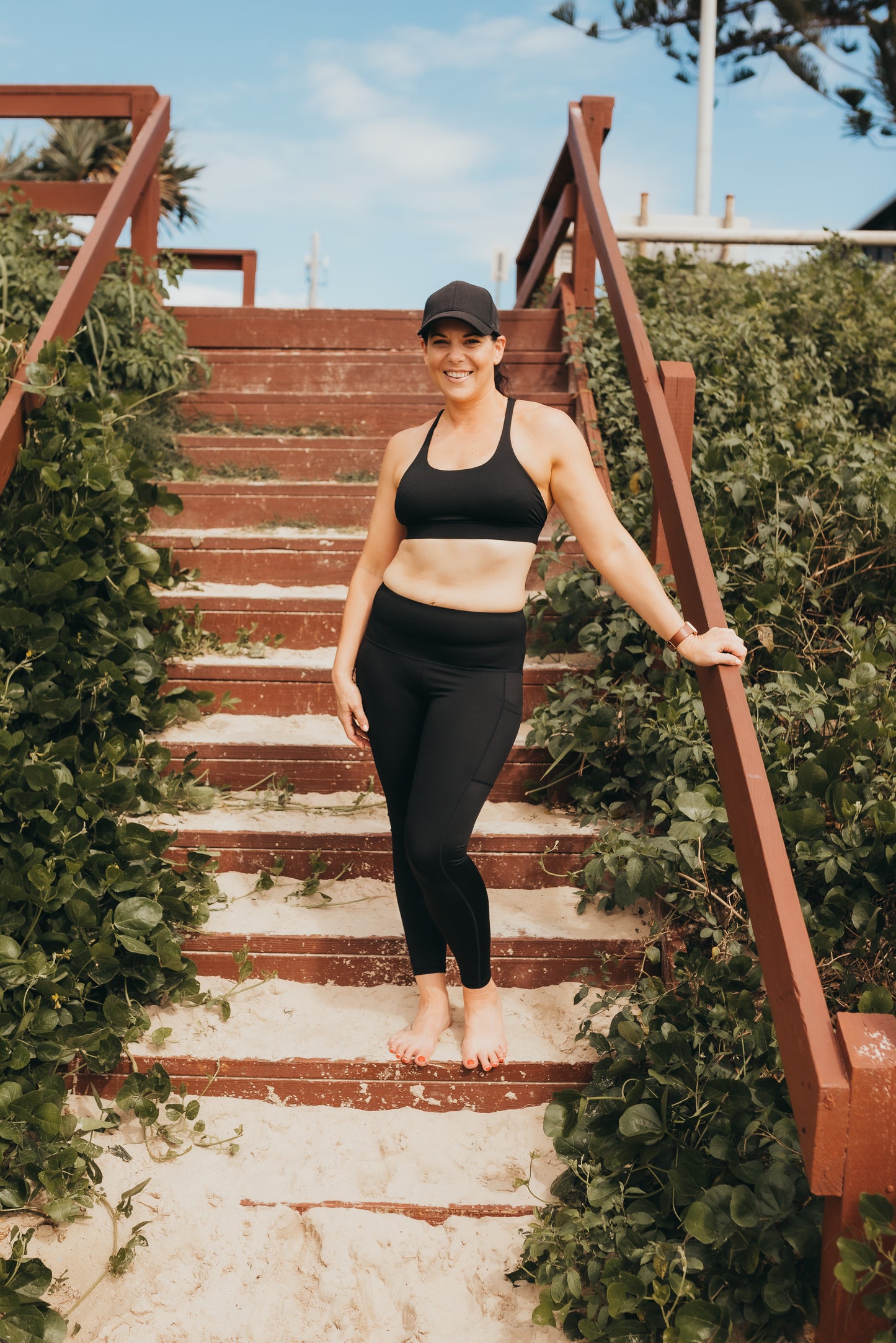 Women at the beach wearing the marlz and me Classic Black Cross Sports Bra and Classic Black Full Length Tights at the beach on a beautiful sunny day.